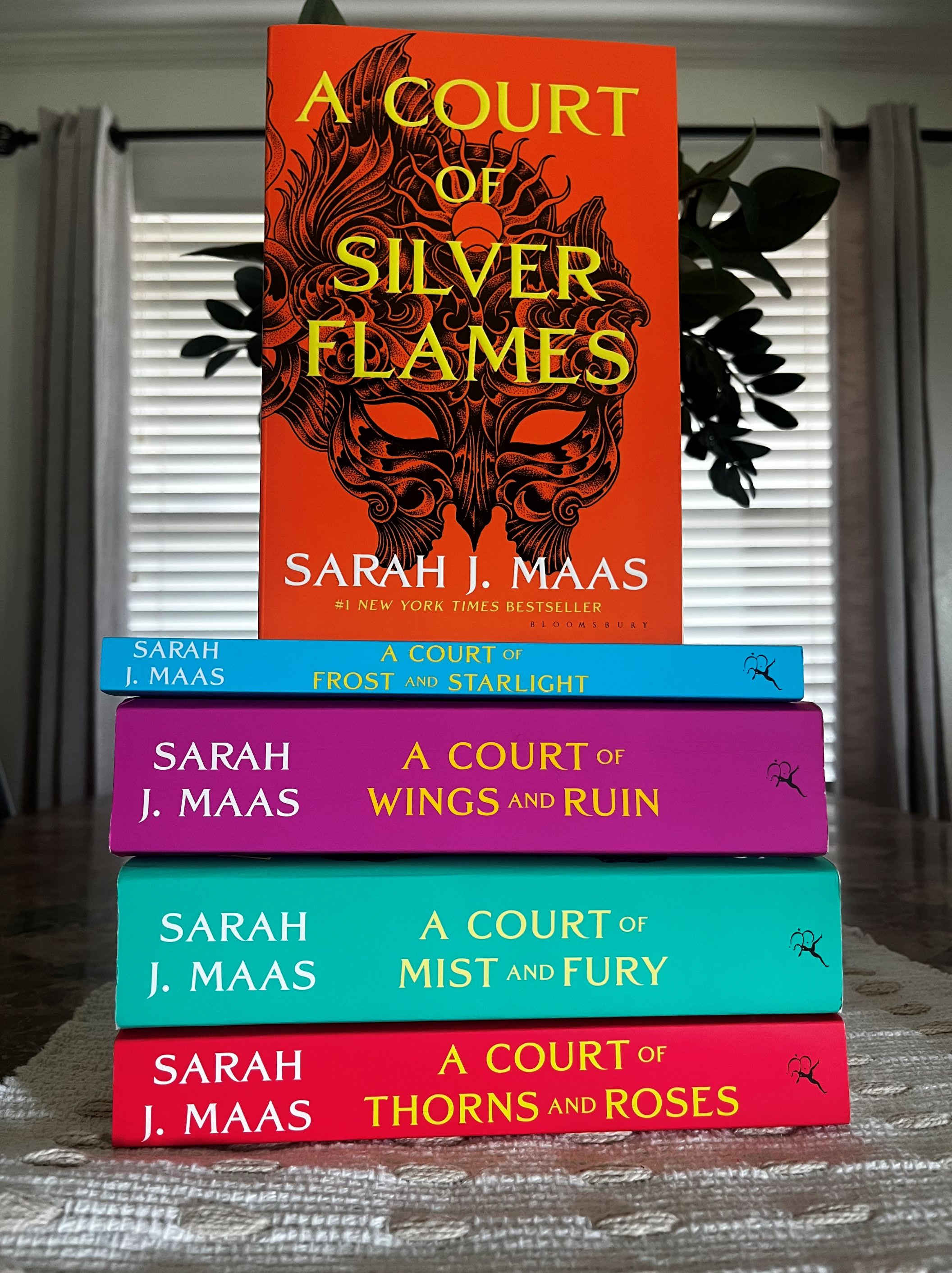 A Court of Silver Flames by Sarah J. Maas displayed upright above the other books in the A Court of Thorns and Roses series.