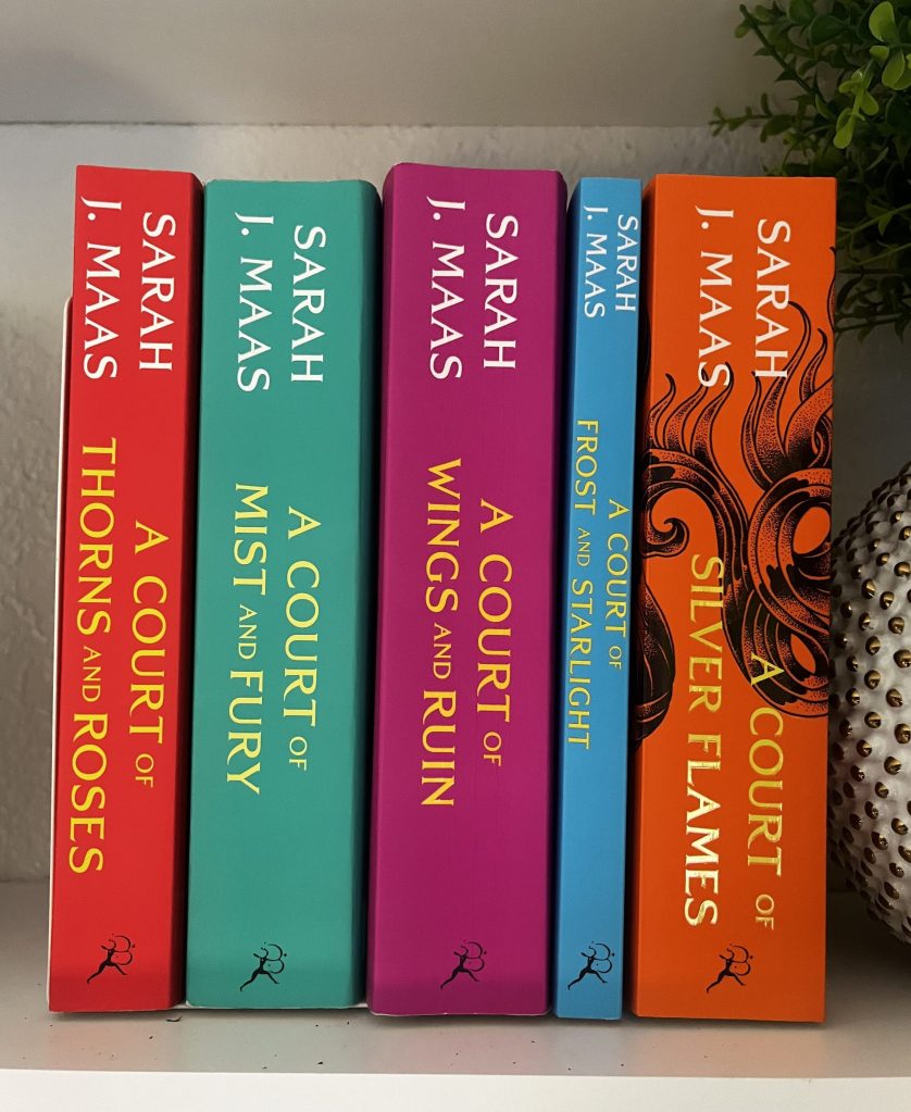 A Court of Thorns and Roses Series by Sarah J. Maas sitting on a bookshelf next to greenery.