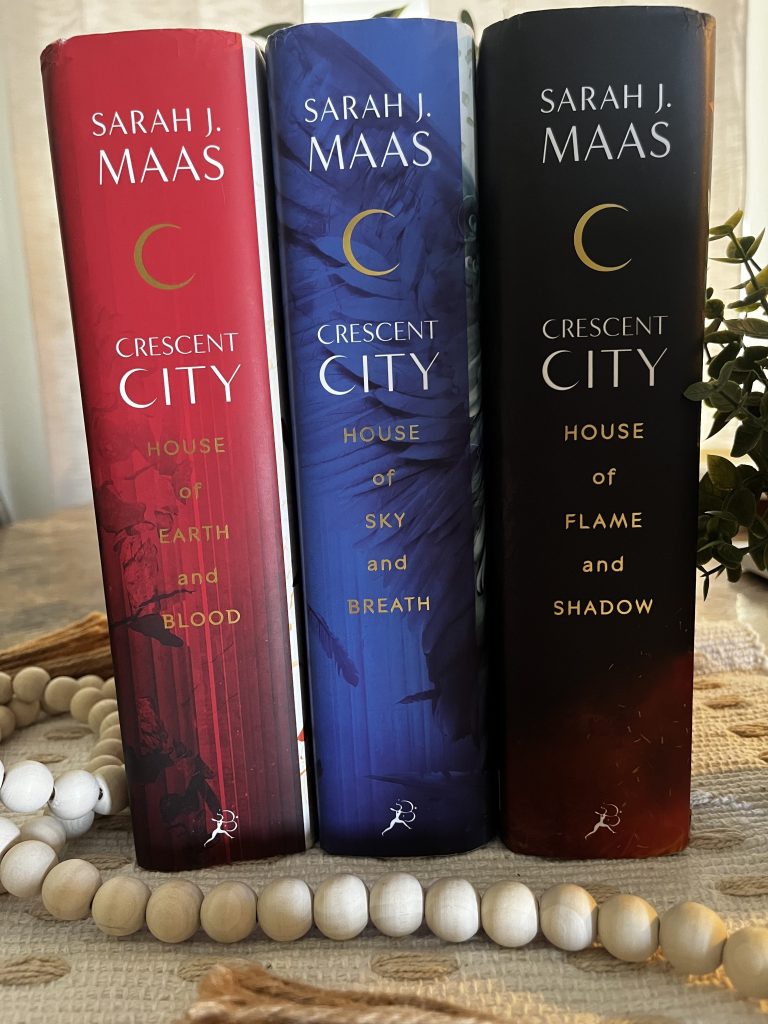 The three Crescent City novels by Sarah J. Maas displayed together on a cream textured fabric.