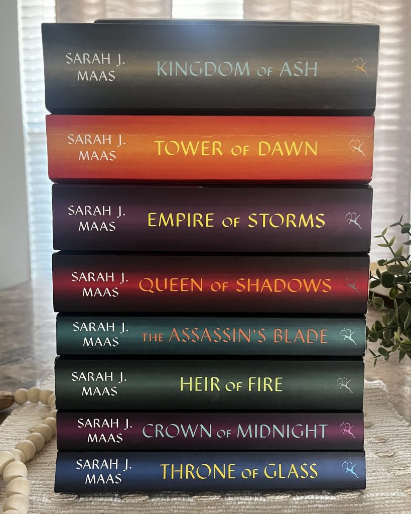 The complete Throne of Glass series by Sarah J. Maas stacked together on a cream textured fabric.