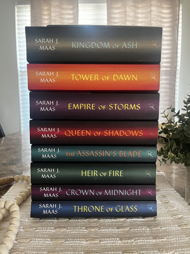 The complete Throne of Glass series by Sarah J. Maas stacked together on a cream textured fabric.